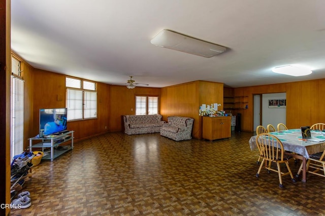 living room featuring dark parquet flooring, ceiling fan, and wood walls