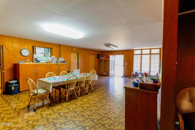 dining space featuring parquet floors and wooden walls