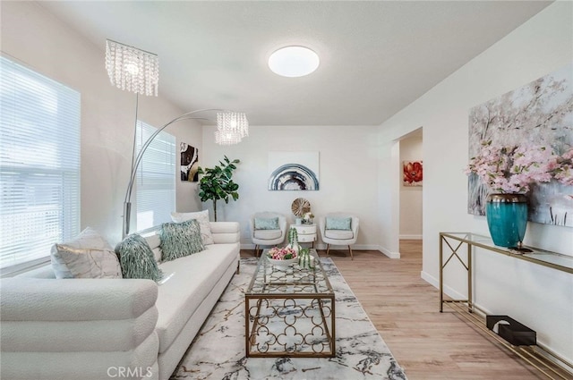 living room with plenty of natural light, light hardwood / wood-style flooring, and an inviting chandelier