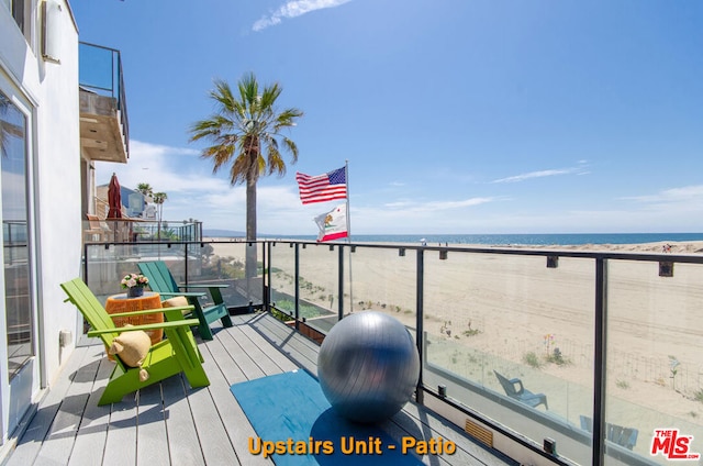 balcony featuring a view of the beach and a water view