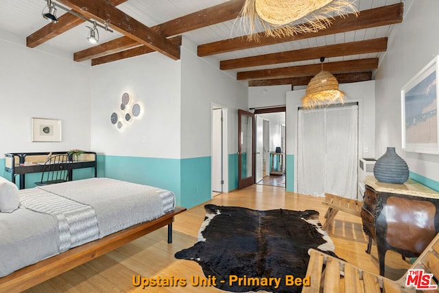 bedroom featuring beam ceiling and light wood-type flooring