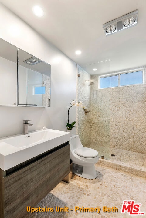 bathroom with vanity, toilet, and a tile shower