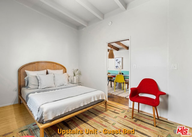 bedroom with hardwood / wood-style floors and beamed ceiling