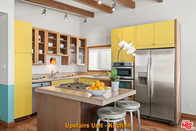 kitchen featuring beam ceiling, dark hardwood / wood-style flooring, a kitchen island, and appliances with stainless steel finishes