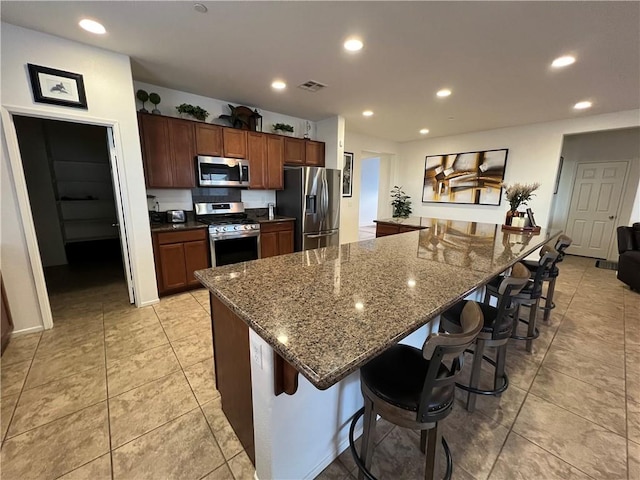 kitchen with a large island, stainless steel appliances, a breakfast bar area, and dark stone counters