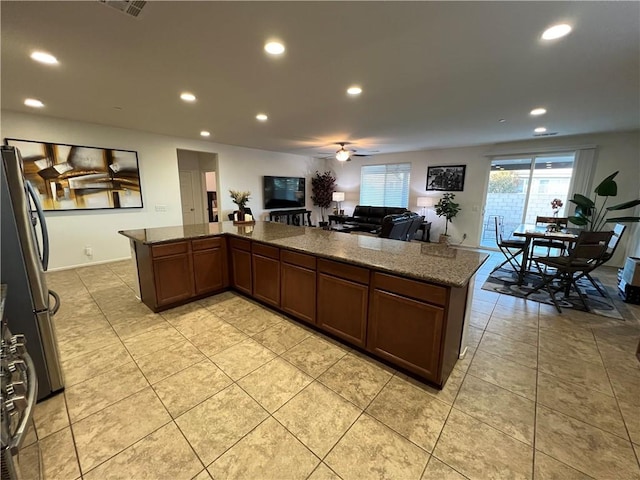 kitchen with ceiling fan, stainless steel fridge, stone countertops, and light tile patterned floors