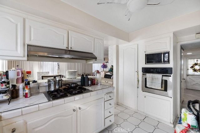 kitchen featuring black appliances, white cabinetry, and tile countertops