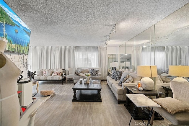 living room featuring wood-type flooring, a textured ceiling, and track lighting