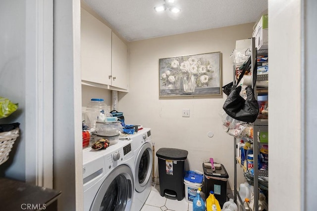 clothes washing area featuring cabinets, a textured ceiling, washing machine and dryer, and light tile patterned floors