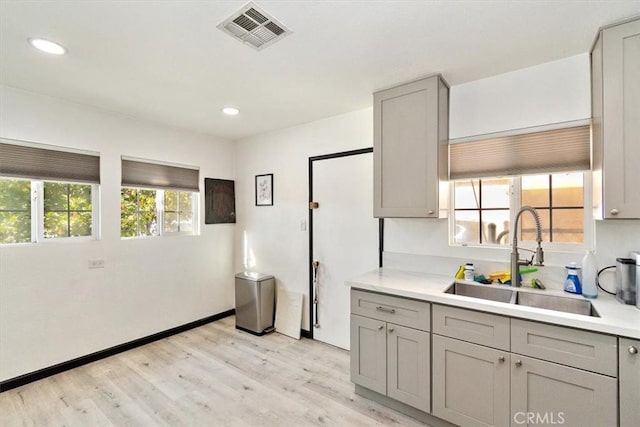 kitchen featuring gray cabinetry, sink, and light hardwood / wood-style flooring