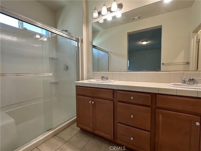 bathroom with tile patterned flooring, vanity, and walk in shower