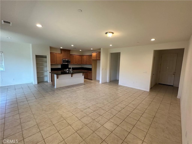 kitchen with a breakfast bar area, a kitchen island with sink, and light tile patterned flooring