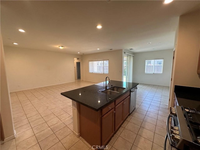 kitchen with gas stove, sink, dishwasher, dark stone countertops, and a kitchen island with sink