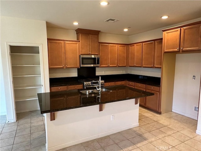 kitchen with a kitchen bar, stainless steel appliances, a center island with sink, and sink