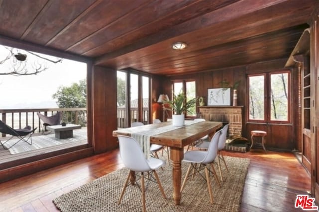 sunroom / solarium featuring a healthy amount of sunlight, wood ceiling, and a brick fireplace