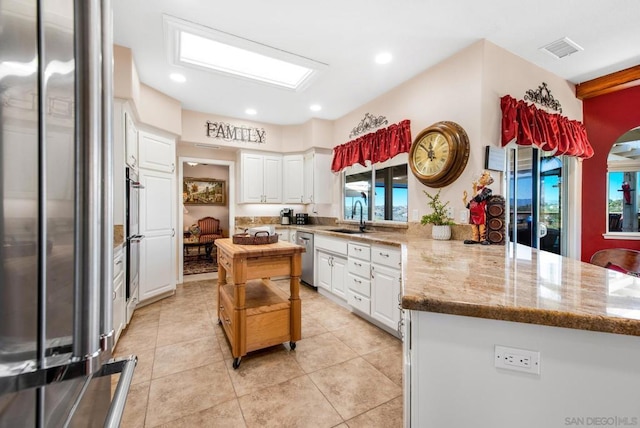 kitchen featuring a center island, white cabinets, sink, appliances with stainless steel finishes, and light stone counters