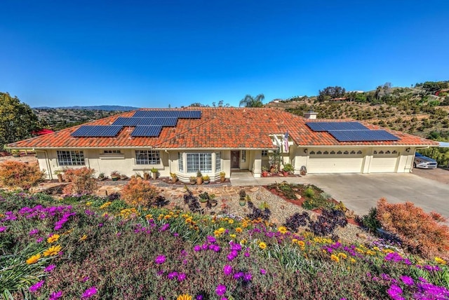 mediterranean / spanish home featuring a wall mounted air conditioner, solar panels, and a garage