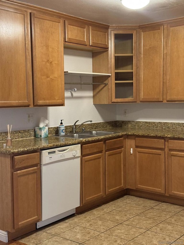 kitchen with sink, white dishwasher, dark stone countertops, and light tile patterned flooring