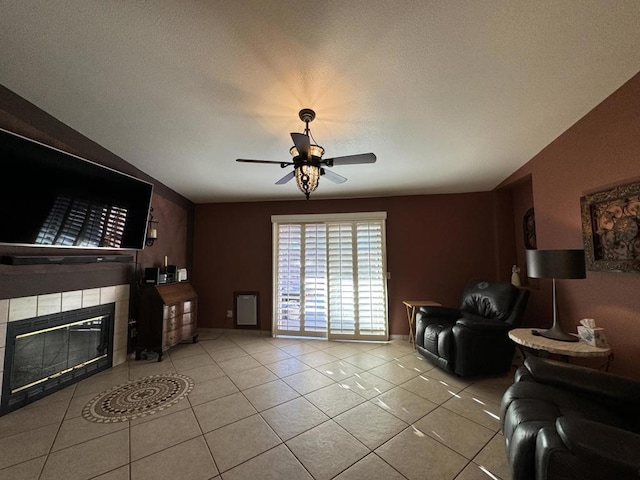 tiled living room featuring a fireplace, a textured ceiling, vaulted ceiling, and ceiling fan