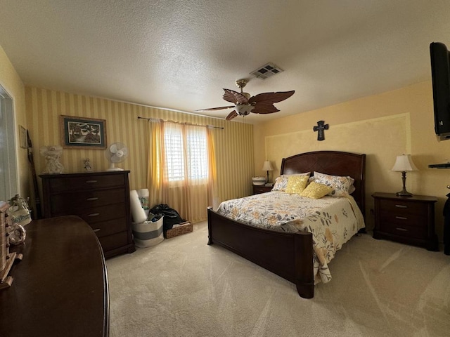 bedroom with ceiling fan, light carpet, and a textured ceiling