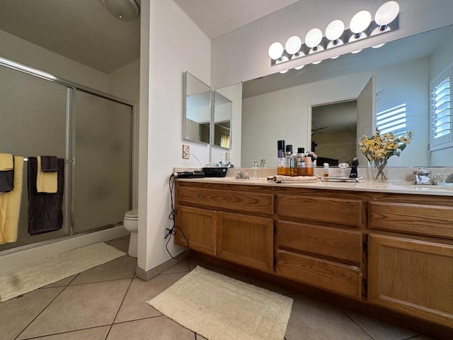 bathroom featuring tile patterned floors, vanity, toilet, and a shower with door