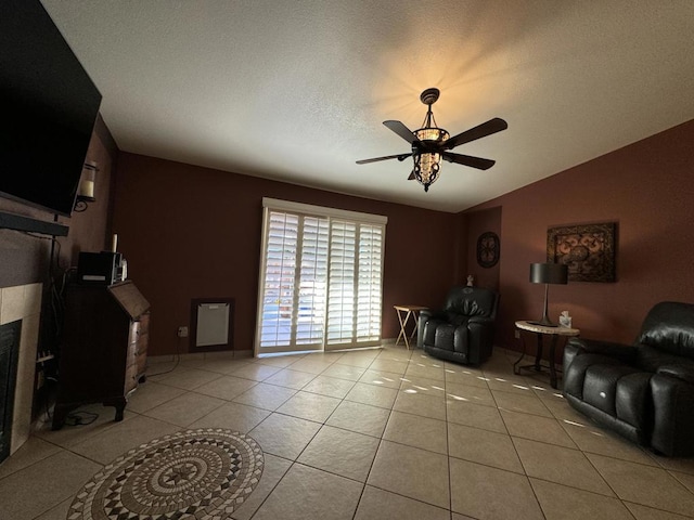 tiled living room with a tile fireplace, a textured ceiling, ceiling fan, and lofted ceiling