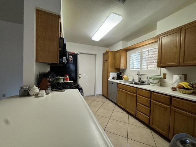 kitchen featuring stainless steel dishwasher, light tile patterned floors, sink, and range with gas cooktop