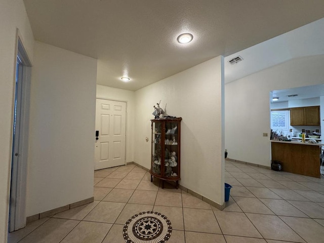 foyer featuring light tile patterned floors and a textured ceiling