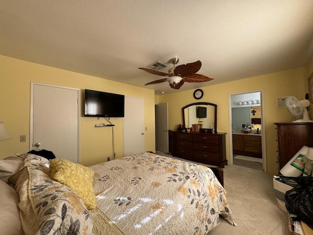 bedroom with light carpet, a textured ceiling, ensuite bathroom, and ceiling fan