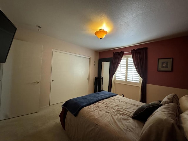 bedroom featuring a textured ceiling, light colored carpet, and a closet