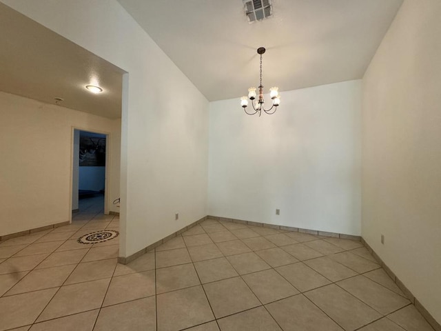 tiled empty room with lofted ceiling and a notable chandelier