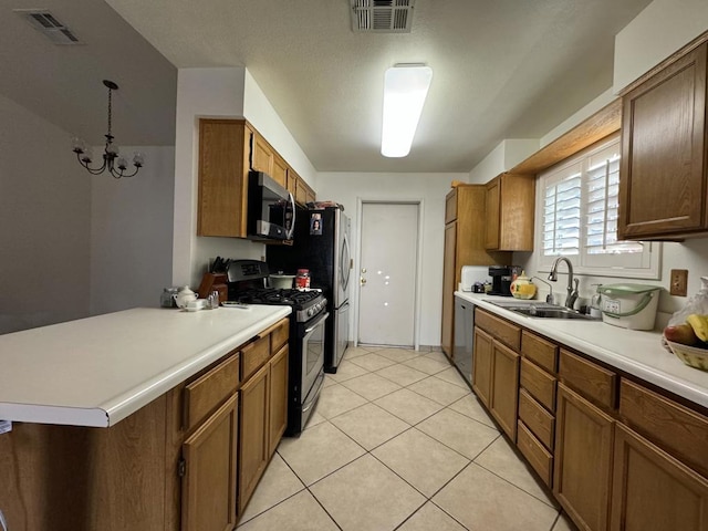 kitchen with sink, stainless steel appliances, an inviting chandelier, kitchen peninsula, and decorative light fixtures