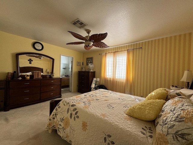 bedroom with ceiling fan, light colored carpet, and a textured ceiling