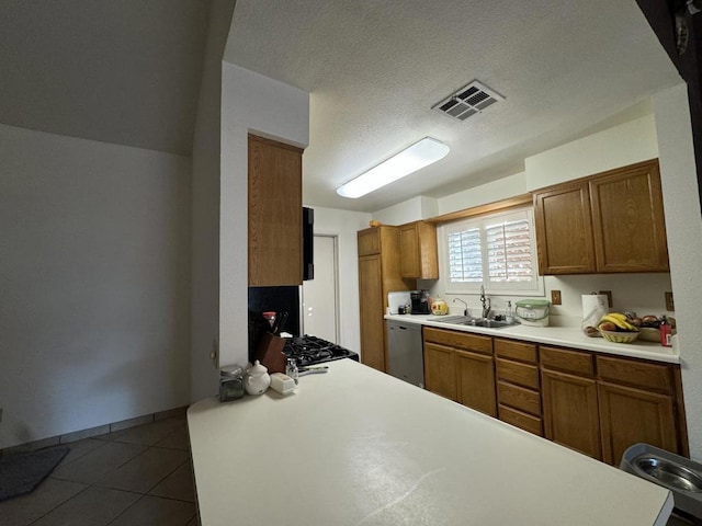 kitchen featuring tile patterned floors, a textured ceiling, stainless steel dishwasher, and sink