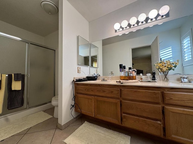 bathroom with tile patterned floors, vanity, toilet, and a shower with shower door