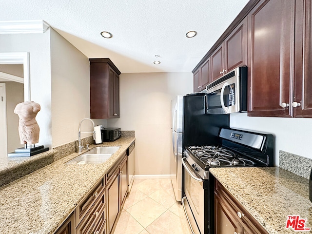 kitchen featuring appliances with stainless steel finishes, light stone counters, a textured ceiling, sink, and light tile patterned floors