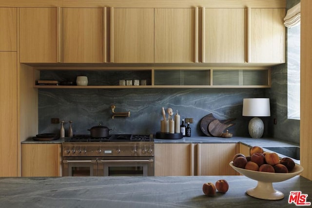 kitchen featuring light brown cabinets, backsplash, and double oven range