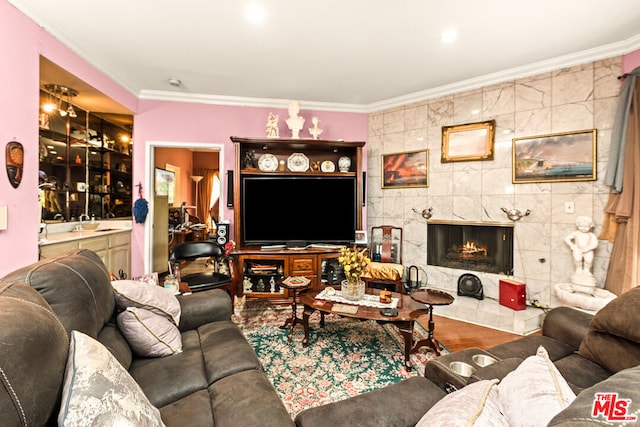 living room with wood-type flooring, crown molding, a tile fireplace, and tile walls