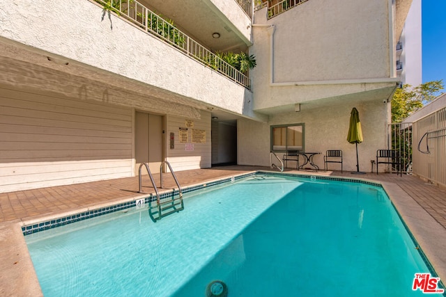 view of swimming pool featuring elevator and a patio