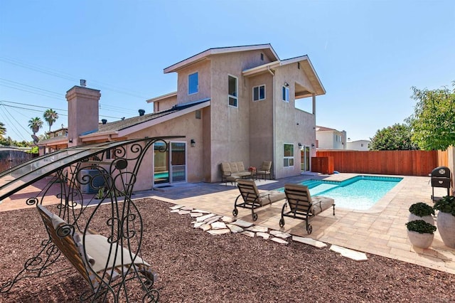 rear view of house with a patio and a fenced in pool