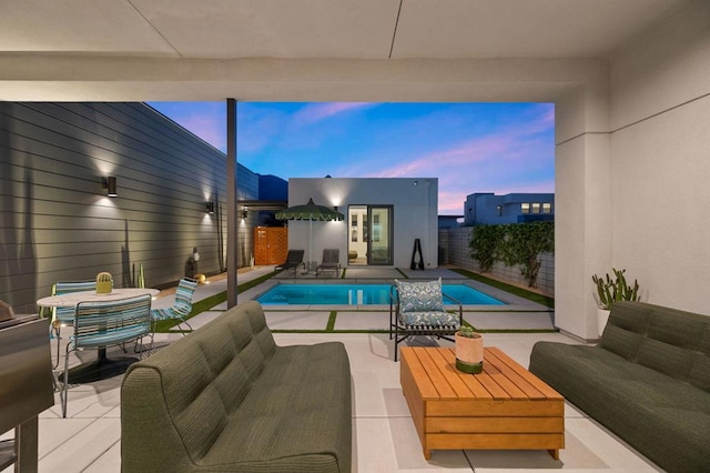 pool at dusk featuring an outdoor living space and a patio