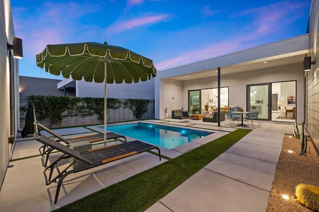 pool at dusk featuring an outdoor hangout area and a patio