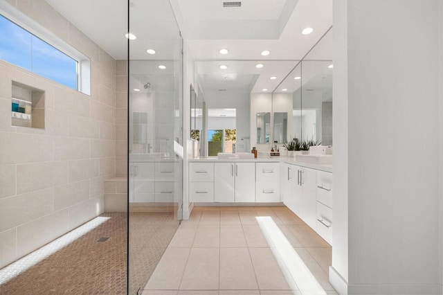 bathroom featuring tile patterned flooring, vanity, and tiled shower