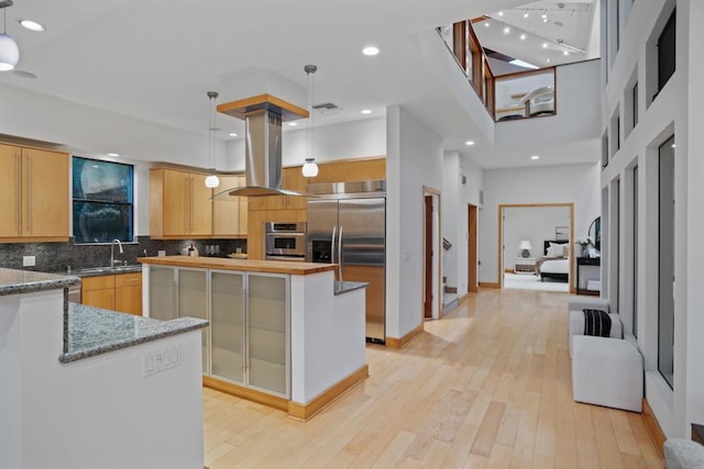 kitchen featuring island exhaust hood, appliances with stainless steel finishes, pendant lighting, and light hardwood / wood-style floors