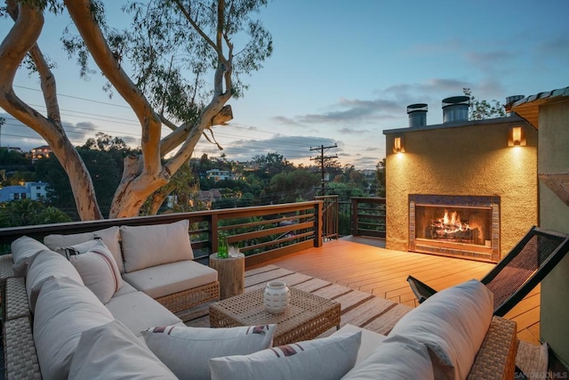 deck at dusk featuring an outdoor living space with a fireplace