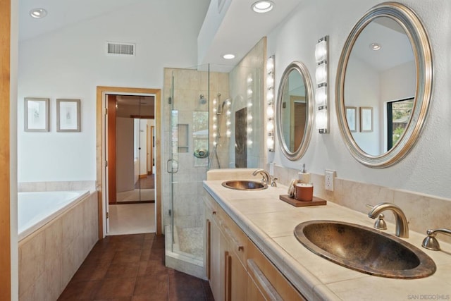 bathroom featuring independent shower and bath, vaulted ceiling, tile patterned floors, and vanity