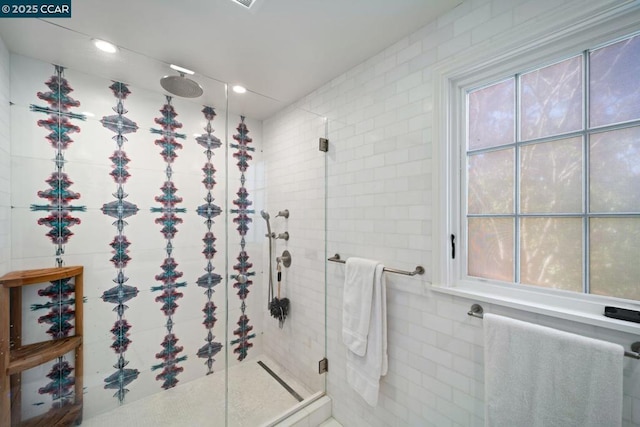 bathroom with an enclosed shower, tile walls, and plenty of natural light