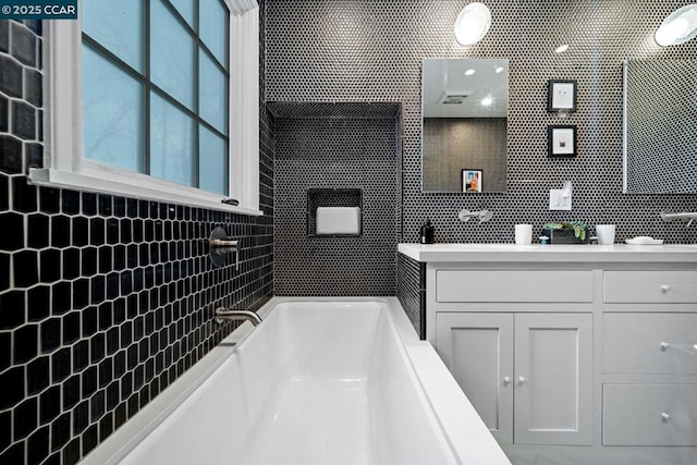 bathroom featuring a bath, tasteful backsplash, and vanity