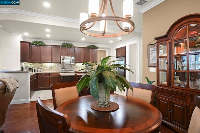 dining area with dark hardwood / wood-style floors, crown molding, and an inviting chandelier