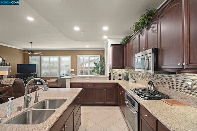 kitchen with light stone countertops, appliances with stainless steel finishes, ornamental molding, and sink